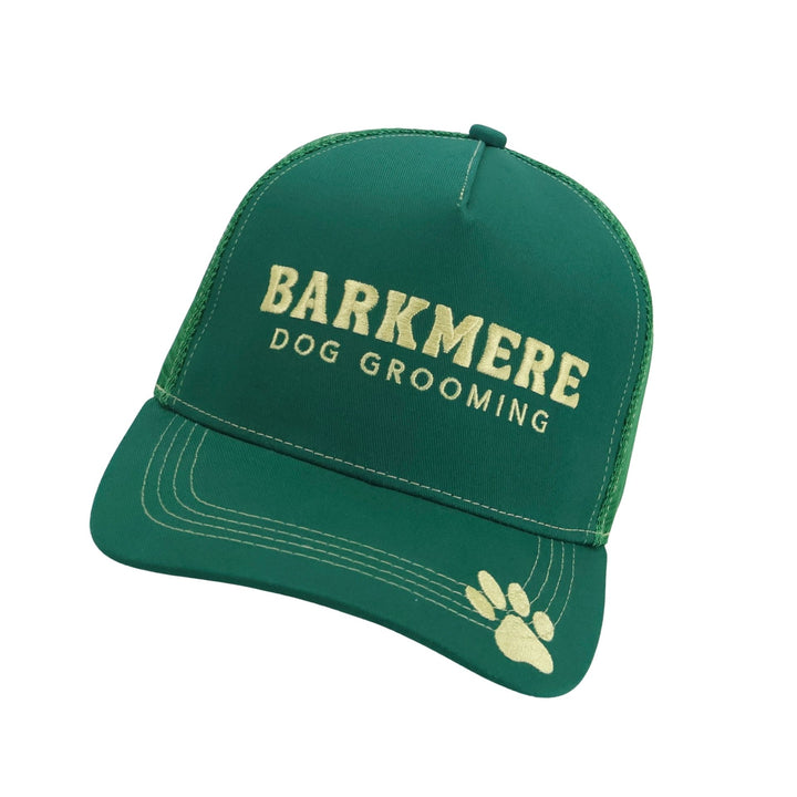Green Barkmere trucker cap seen front on, cream embroidered wordmark and a paw print on the brim